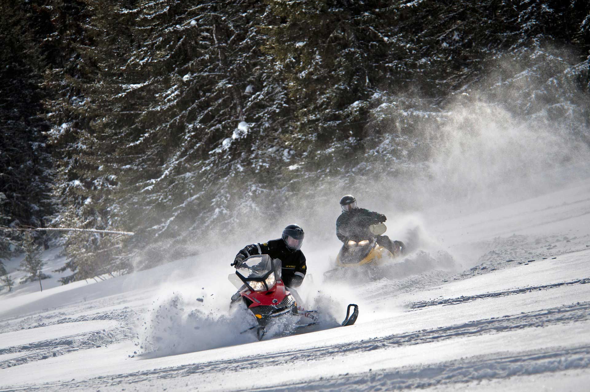 Two snowmobilers on a snowy mountainside in South Dakota