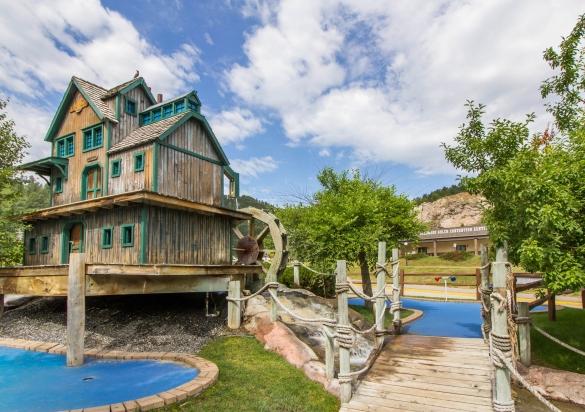 Water and a rustic looking building sit as part of the mini golf course
