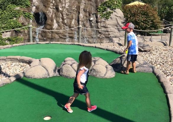 Children walk on the green turf of this mini golf course